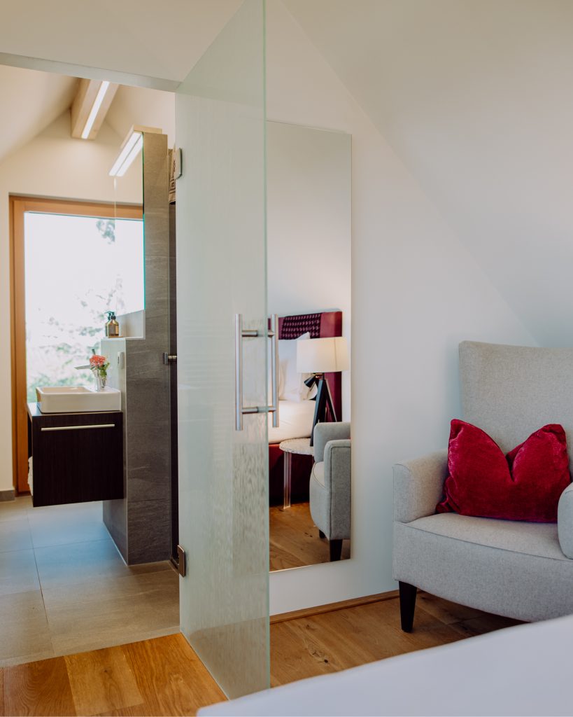 Ein Sessel im Eck sowie ein Einblick ins Badezimmer vom Sulzblick Zimmer