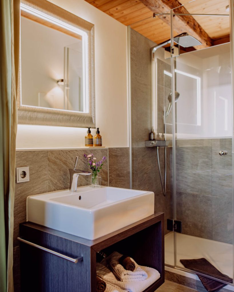 Badezimmer mit Waschbecken und Waschtisch, neben eine Dusche